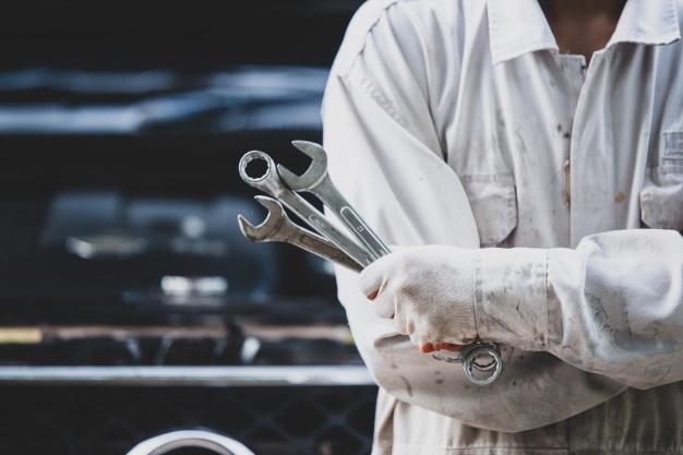 Car repairman wearing a white uniform standing and holding a wrench that is an essential tool for a mechanic Free Photo